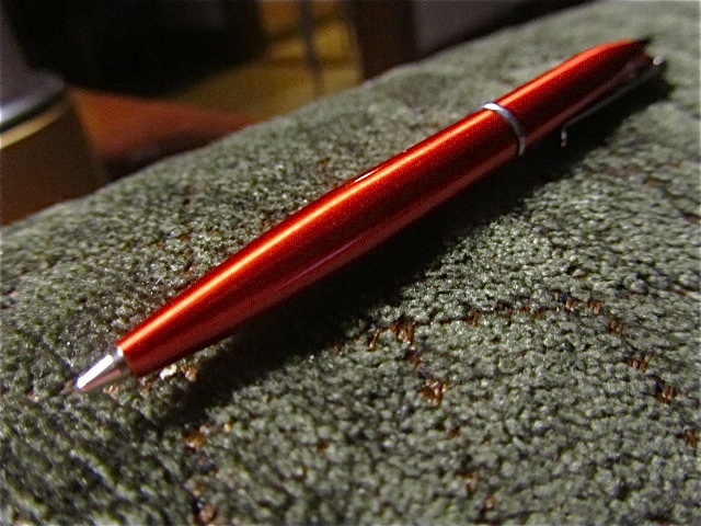 red pen laying on grey cloth with metal tip