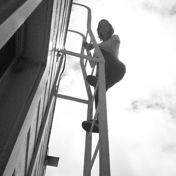 a woman is climbing on the side of a building