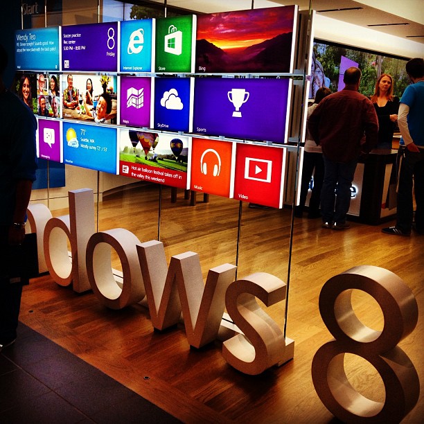 people looking at multiple microsoft windows 8 displayed in a store