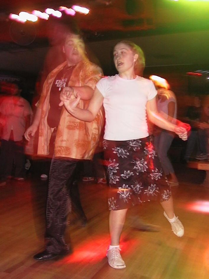 people dance with one another on a wooden floor