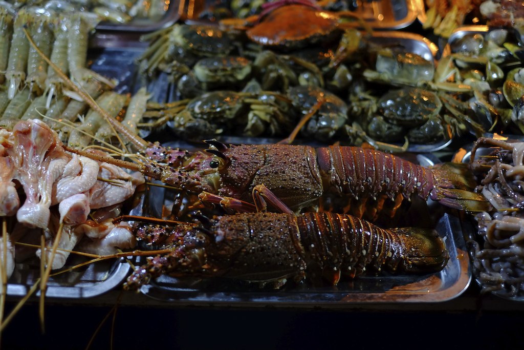 several lobsters, shrimp and other edible items on plates