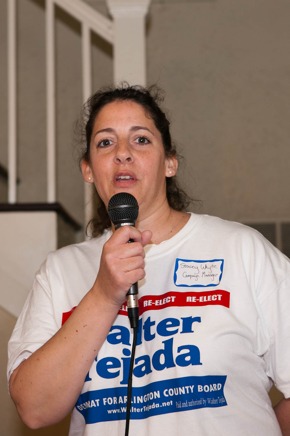 a woman is talking into a microphone while standing next to stairs