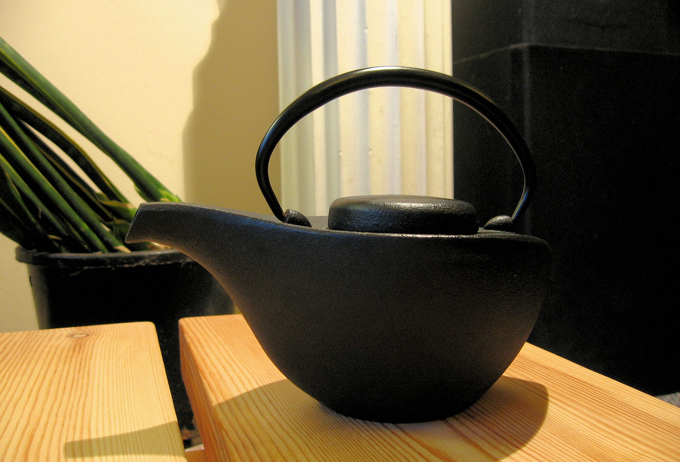 a pot sitting on top of a wooden table next to a plant