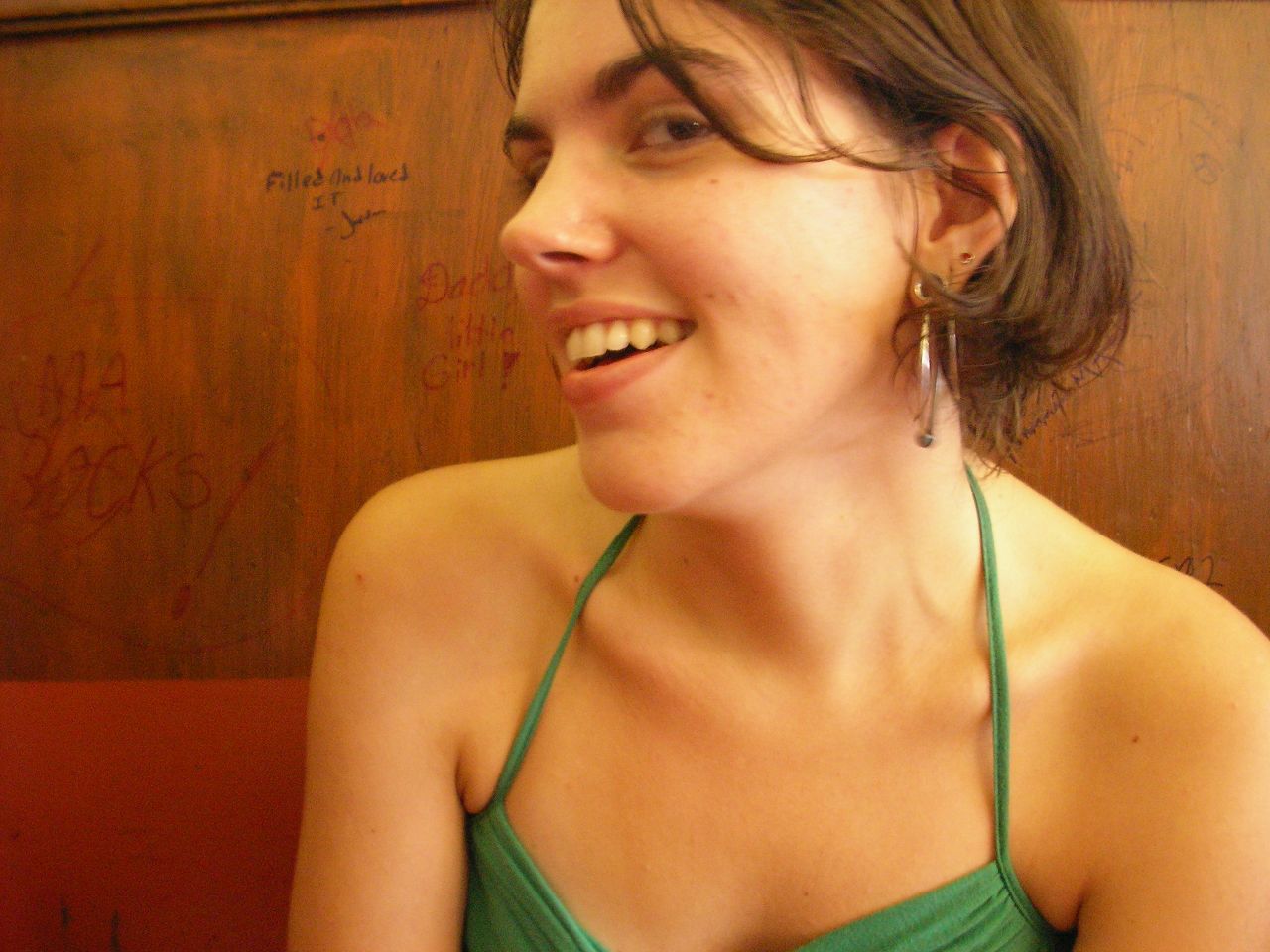 a woman with ear buds on and wearing a green top