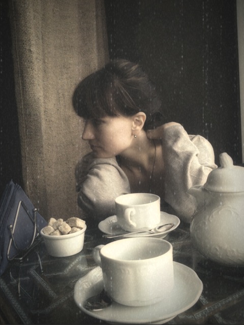 a woman sitting at a table with some white dishes and cups