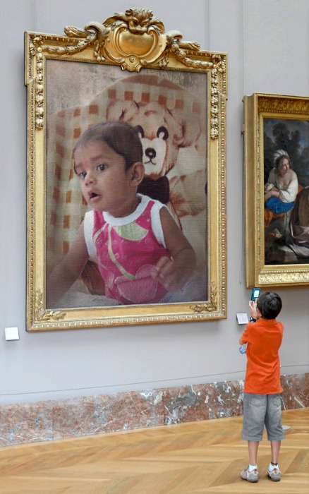a small child taking a picture of a big painting