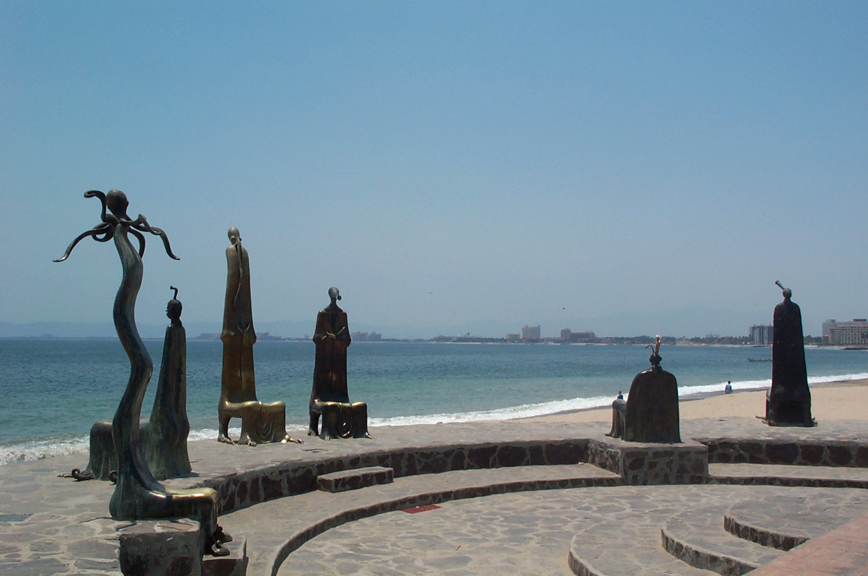 a statue sitting on top of a beach next to the ocean