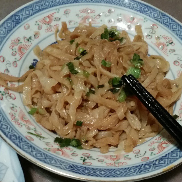 a dish on a table with chopsticks and some noodles