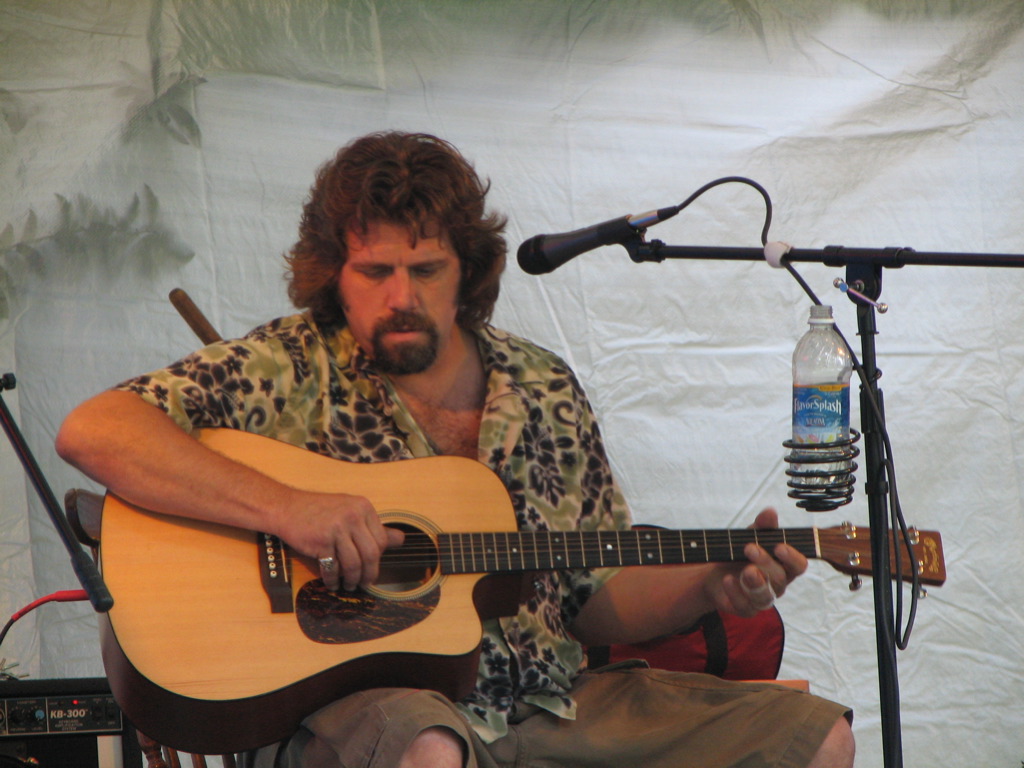 a man sitting in front of a microphone playing a guitar