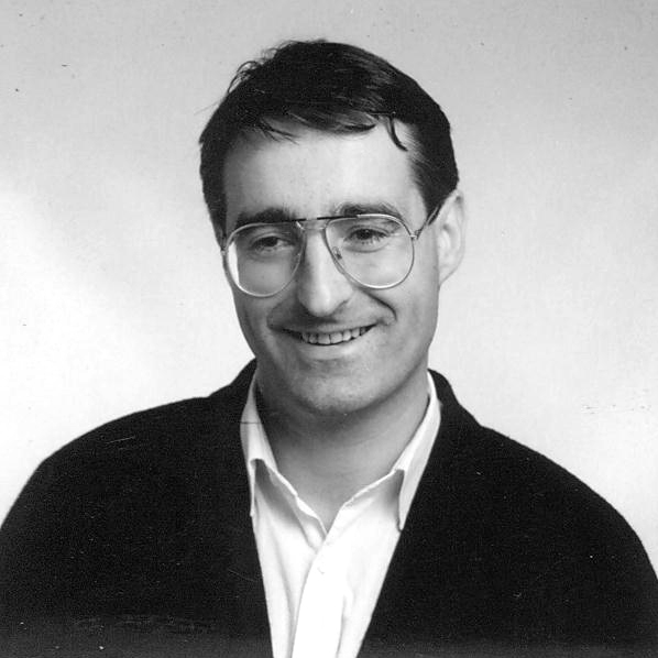 black and white po of a man wearing glasses smiling