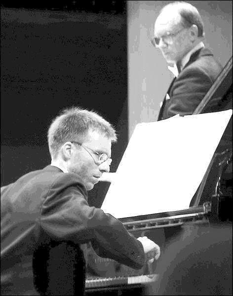 two men playing keyboards on stage at concert