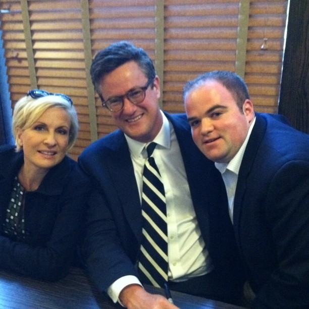 two men and one woman sit together and smile