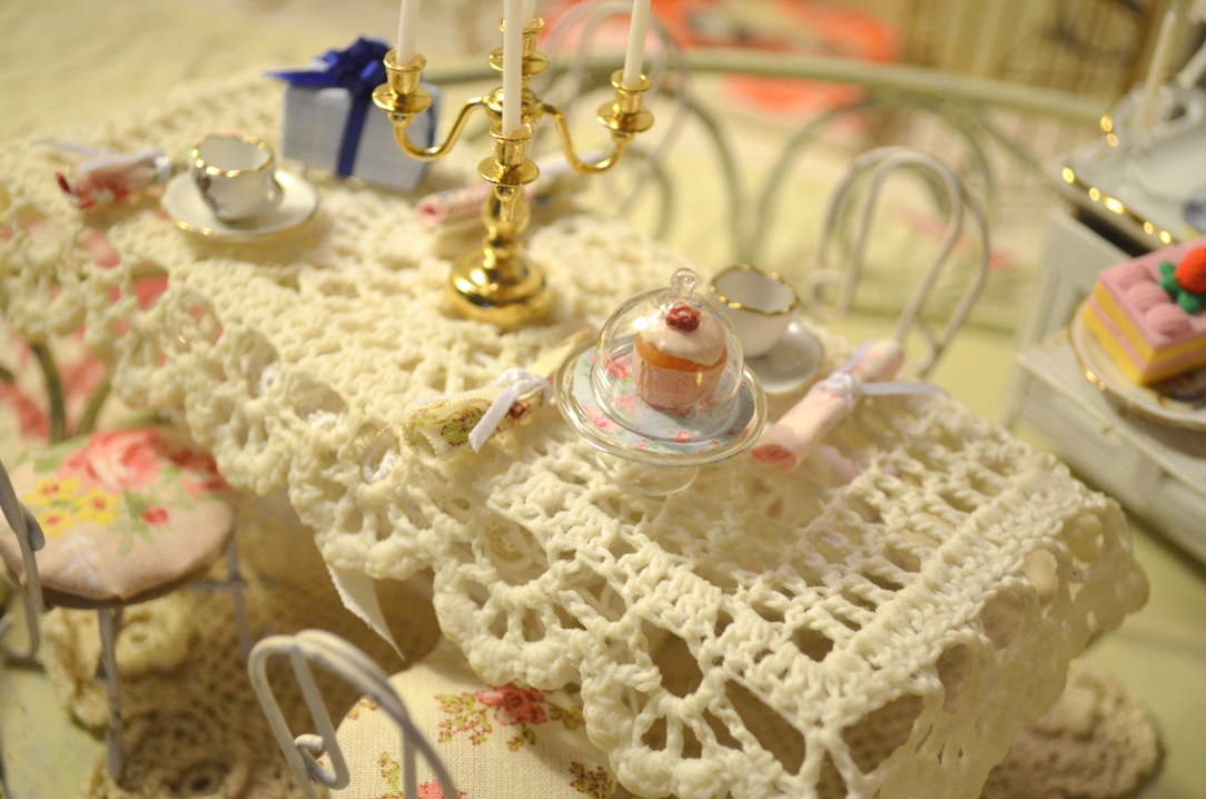 a small dollhouse covered in doily sitting on a table