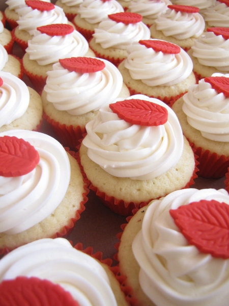 many cupcakes decorated with white and red icing