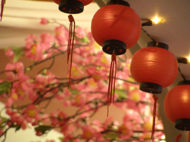 some red lanterns hanging from a ceiling with flowers