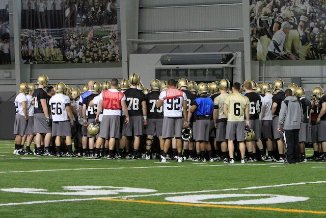 many football players stand in a team huddle