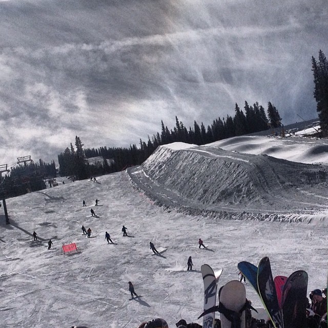 people snowboarding down a hill under a cloudy sky
