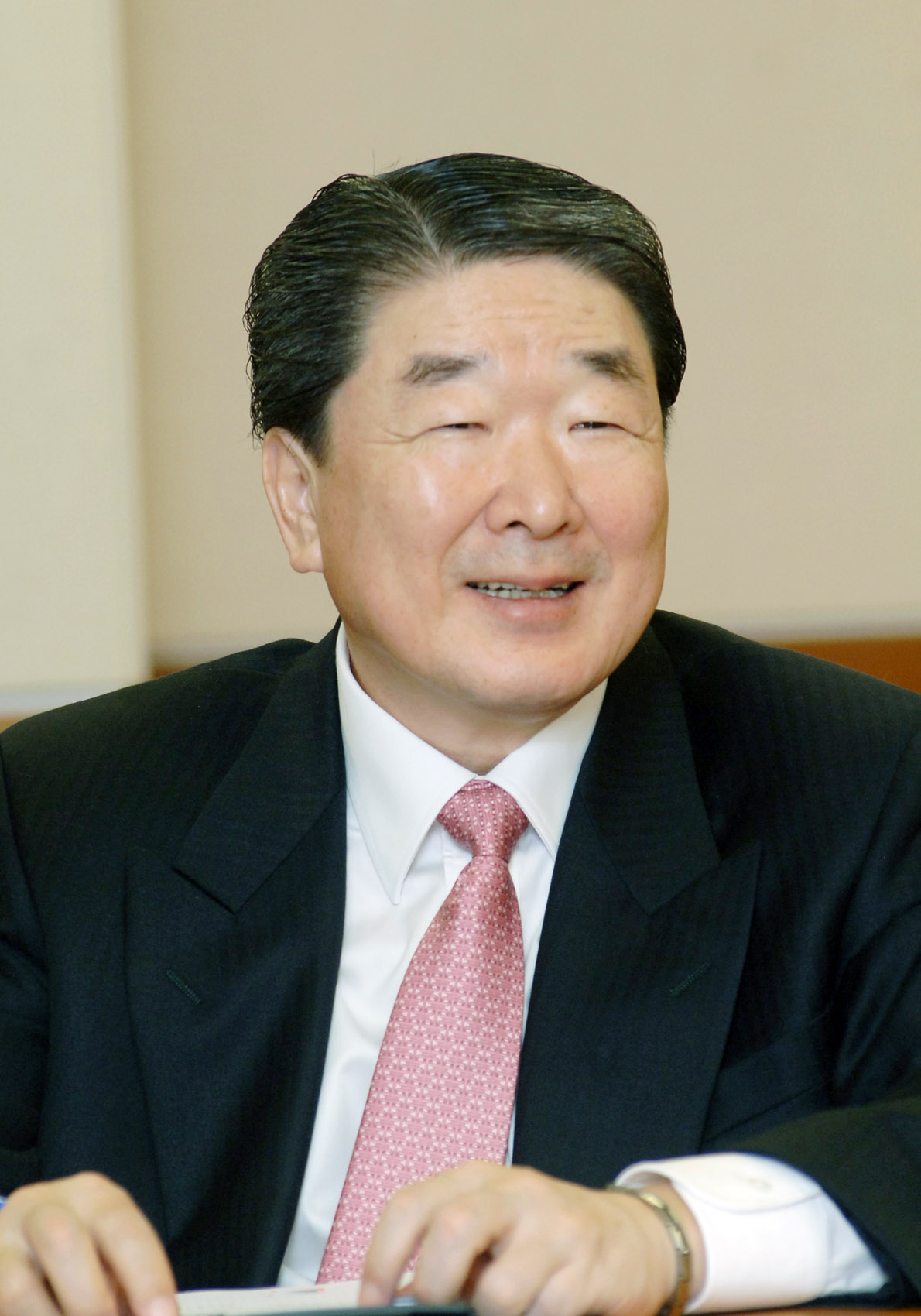 asian businessman in suit and pink tie sitting down