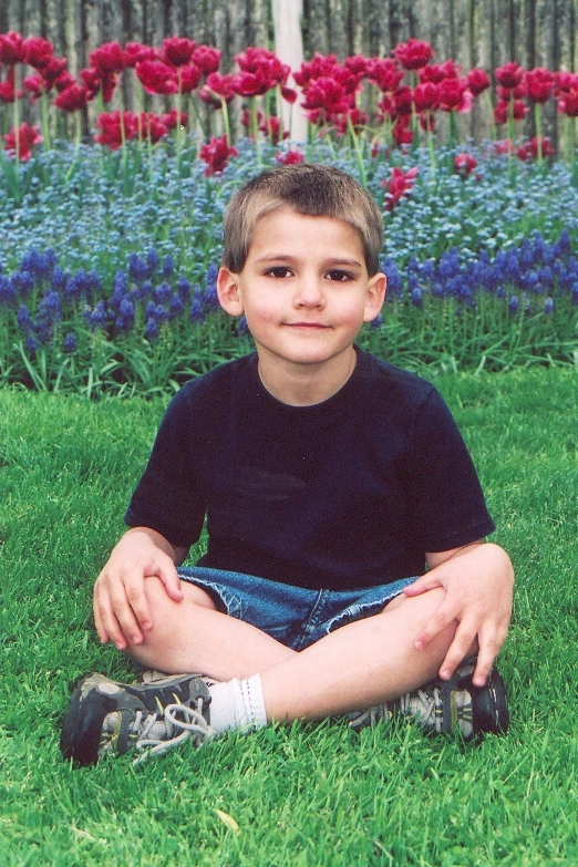 a  is sitting on the grass next to flowers