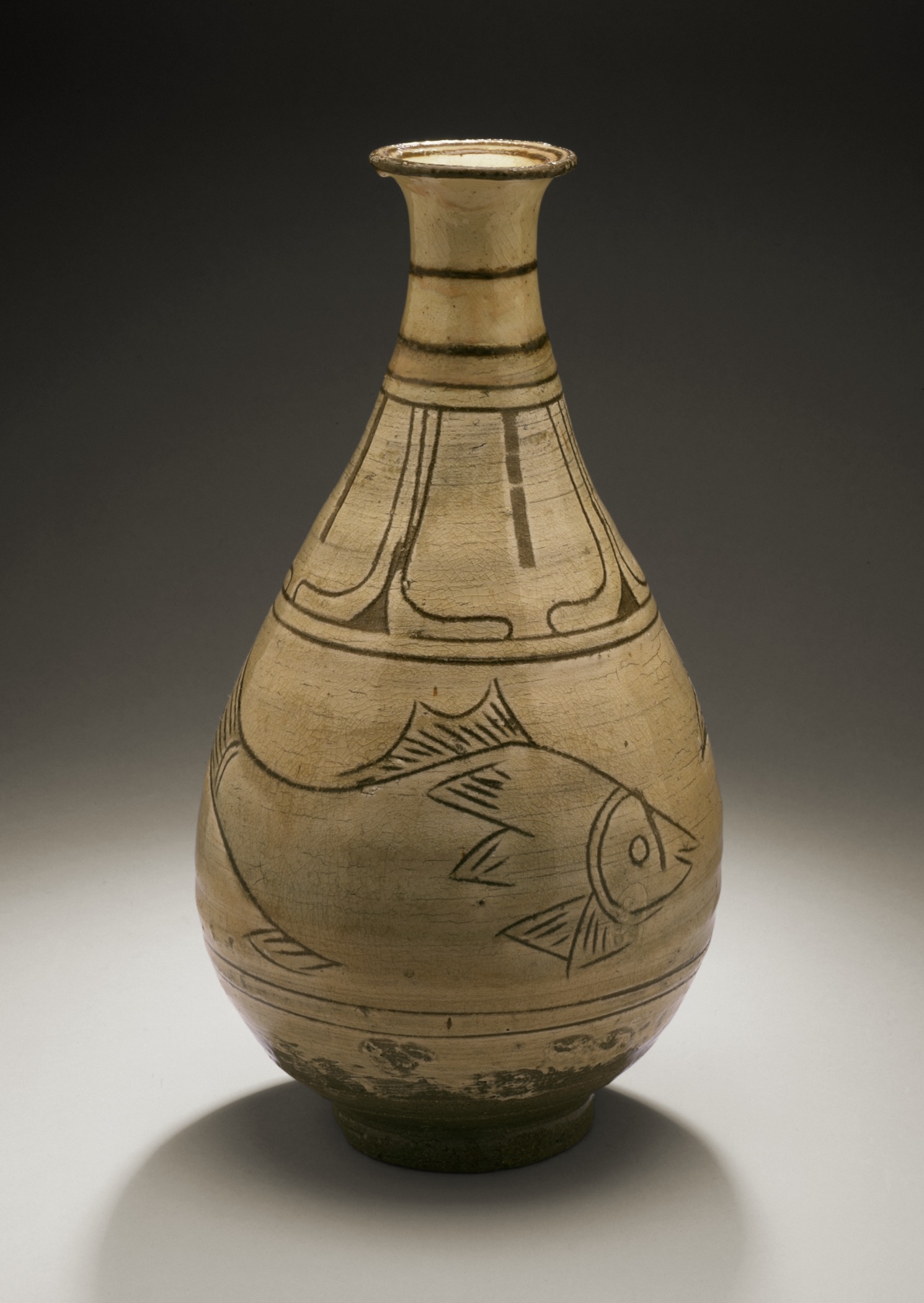 a gold vase on a black background with a fish design