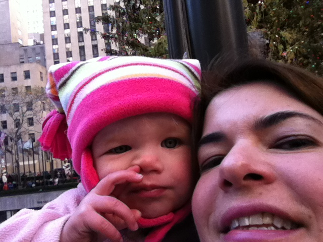 a woman holding a baby in front of city buildings