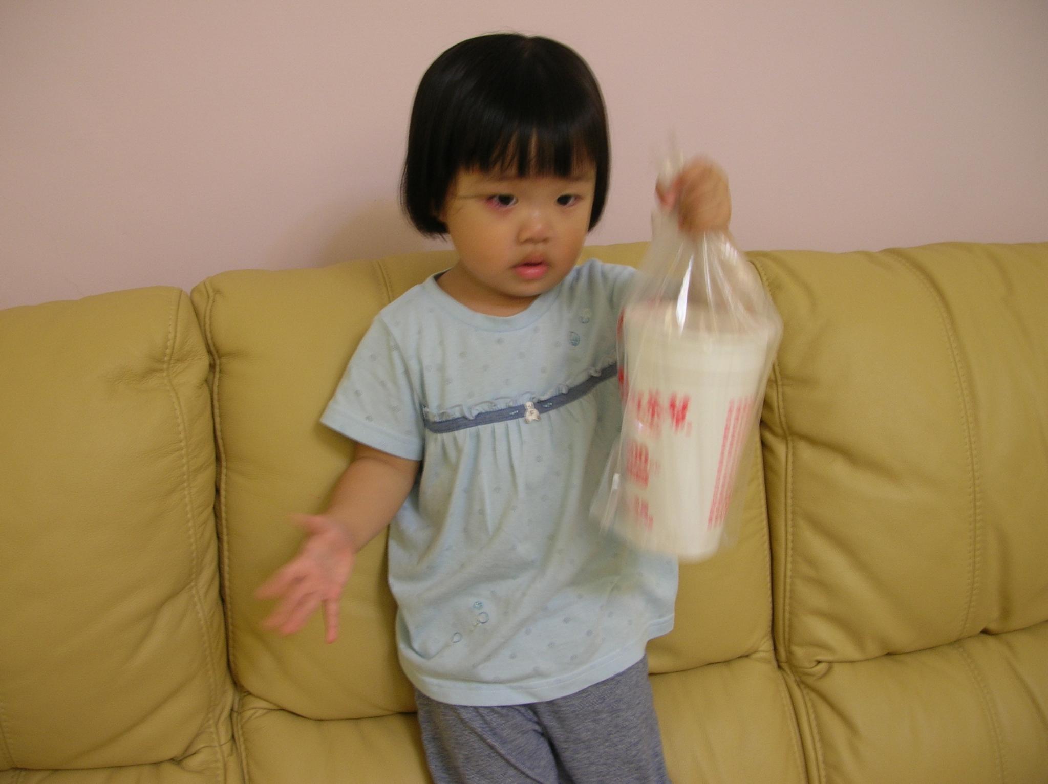 a little  holding a milk in front of him