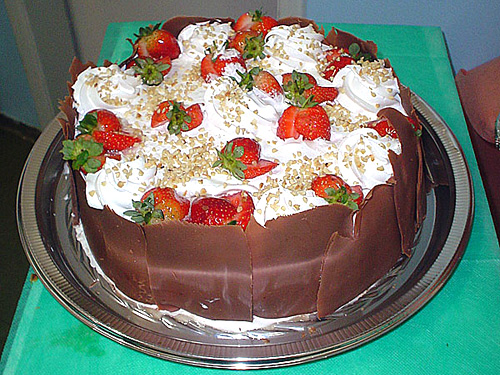 a chocolate cake with strawberries on it and cream frosting