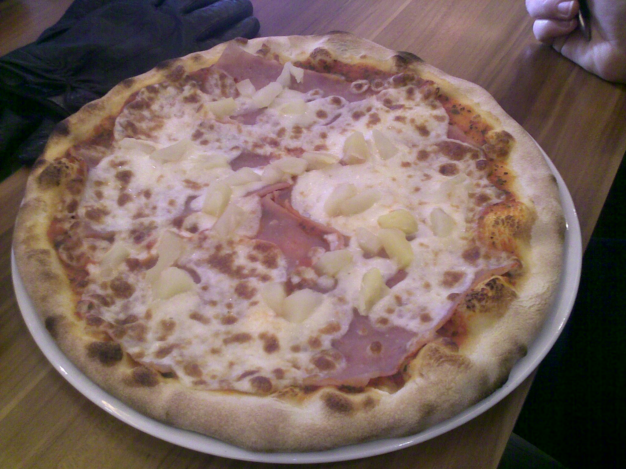 a pizza with ham on it on top of a wooden table