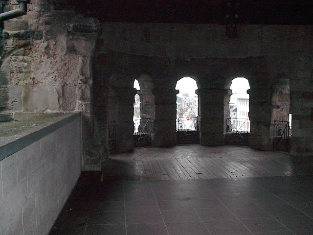a stone tunnel has three arched windows that look out to other buildings