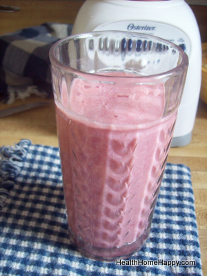 a pink smoothie is in a small glass on a towel
