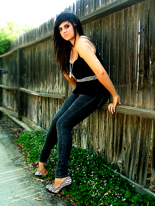 a woman leaning against a wooden fence with her feet on the fence