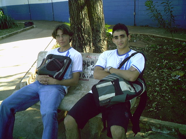 two young men sitting on a bench by a tree