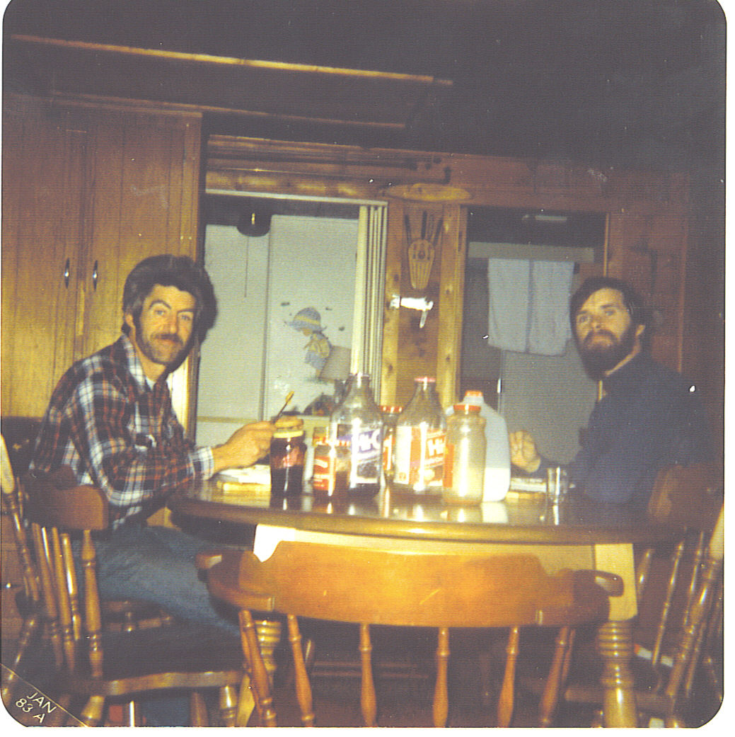 two men sitting at a table with beers around them