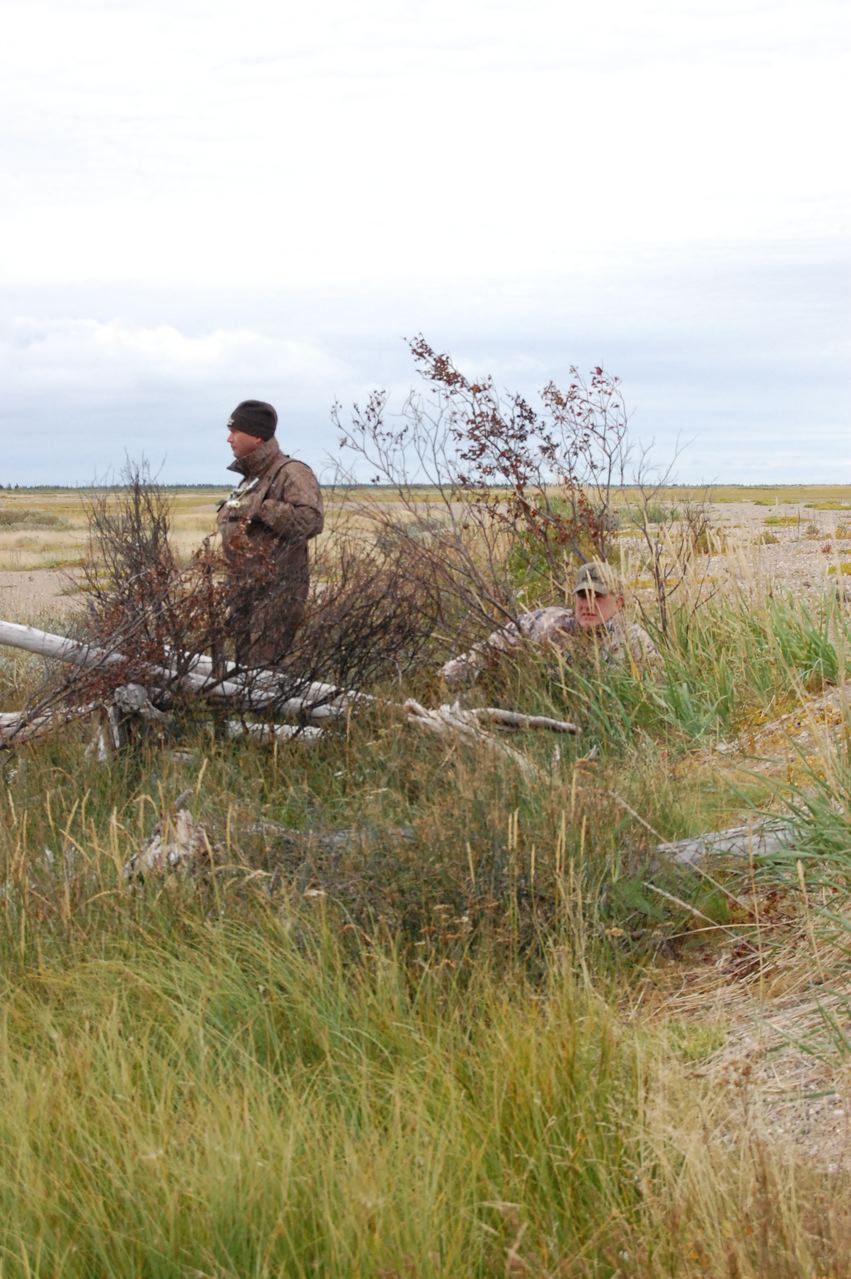 a man stands in the grass near an overturned piece of wood