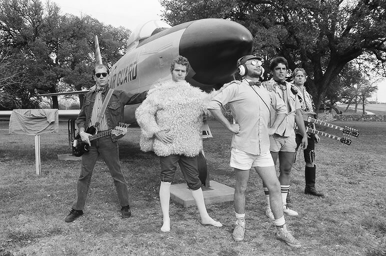 a black and white po of men posing for a po with an airplane