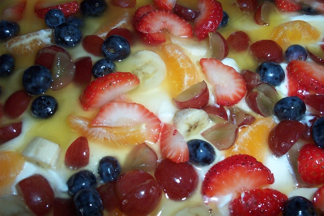 the fruit salad is topped with bananas, blueberries, strawberries, and oranges