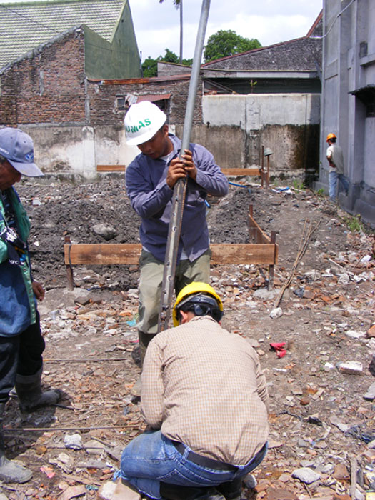 three people in helmets holding up a street pole