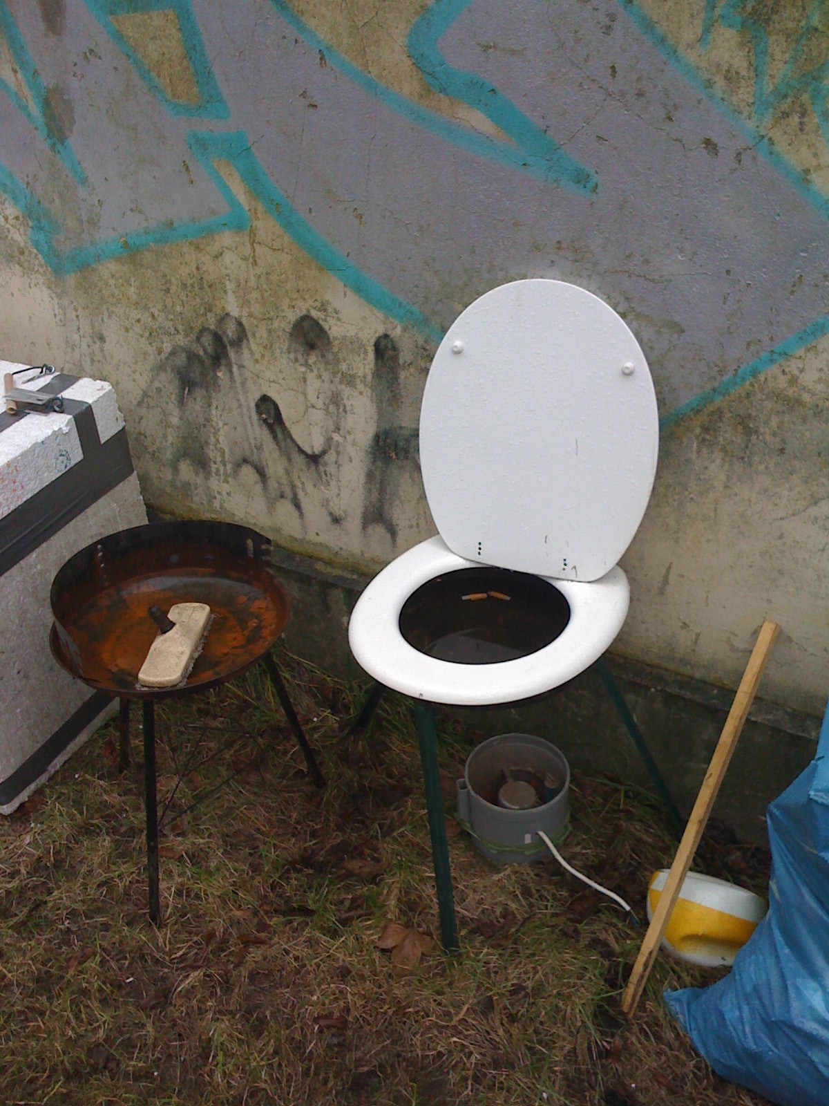 a toilet seat up in a dirty stall