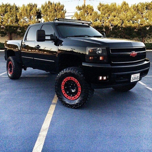 black truck with red wheels parked in a parking lot