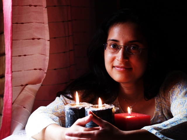 woman sitting in front of candles and smiling for the camera