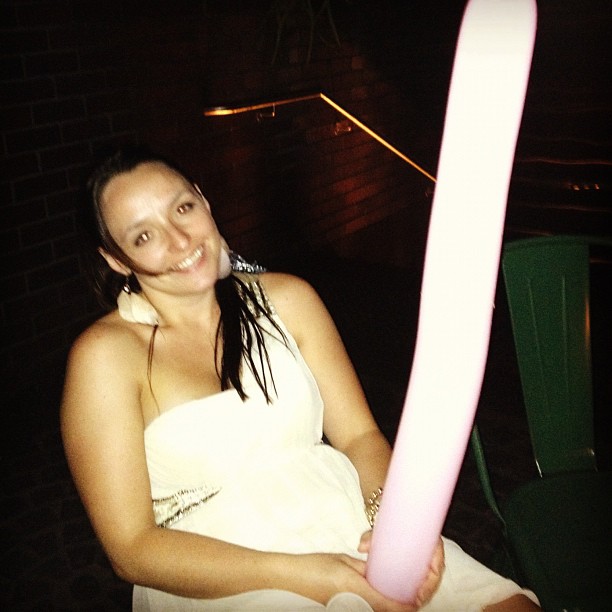 a girl in a white towel sitting with a pink umbrella