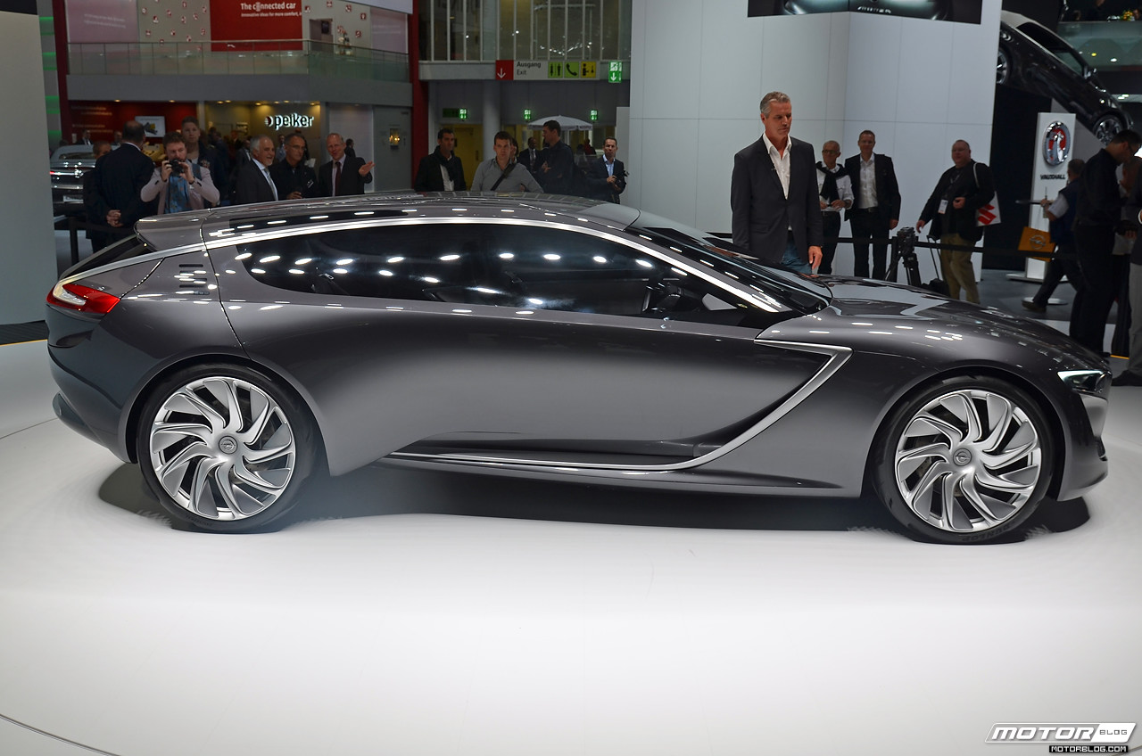 people gather around the futuristic car at an automobile show