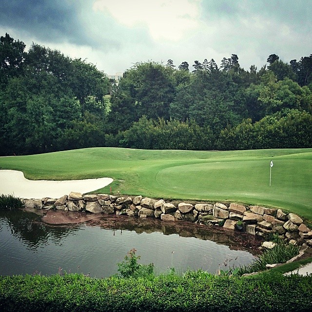 a green on a course with water and some rocks