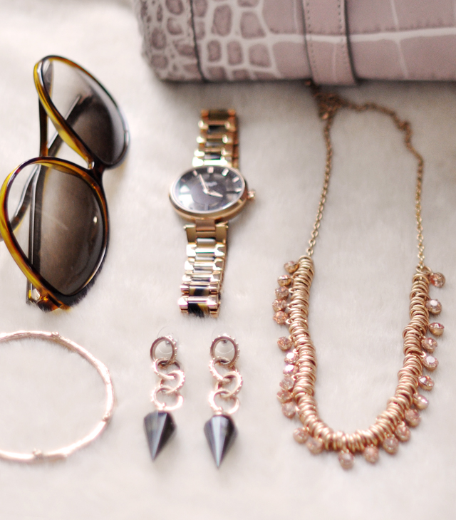 many accessories on a white table with a pink purse