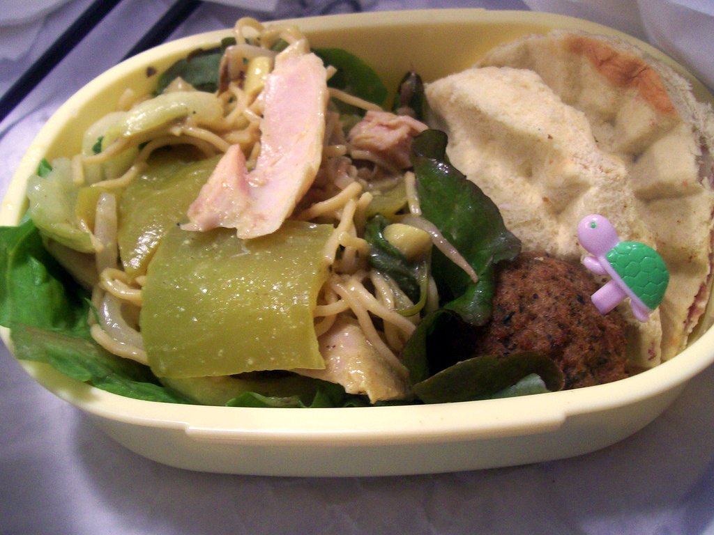 a tray is filled with noodles, meat and veggies