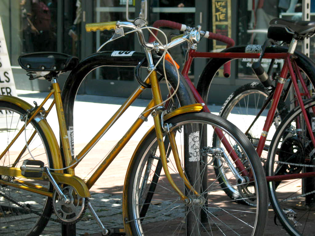 a couple of parked bikes are standing near each other