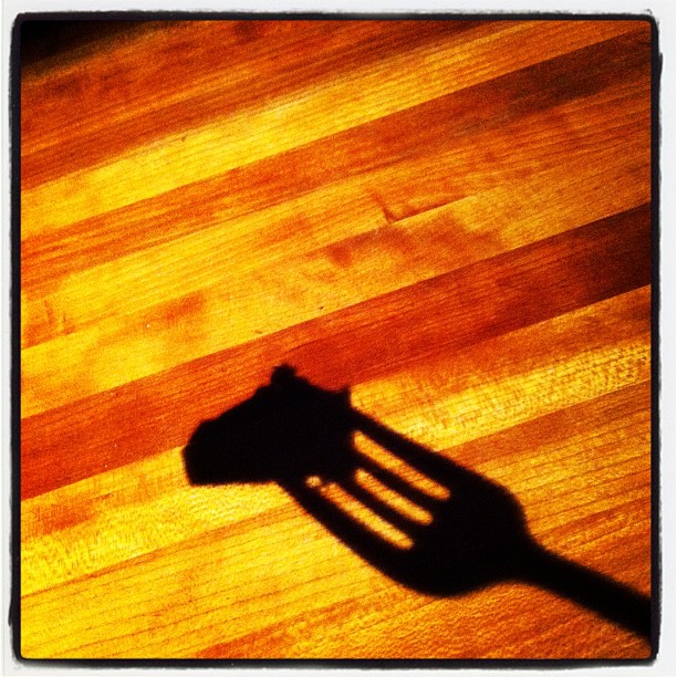 a cat casts a shadow on a wooden table