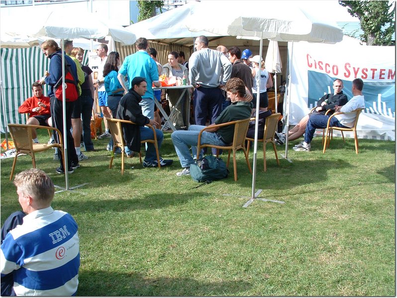 there are many people sitting at tables in the grass