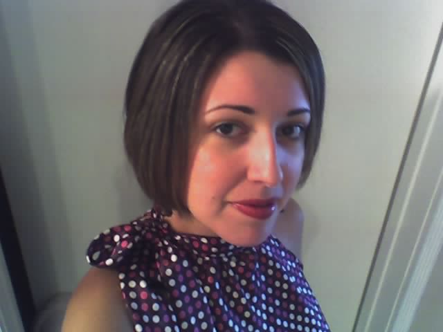 a woman wearing a polka dot shirt is looking into the camera