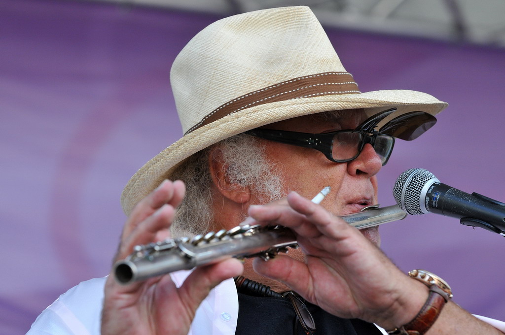 a man in glasses playing the harmonica at an outdoor event